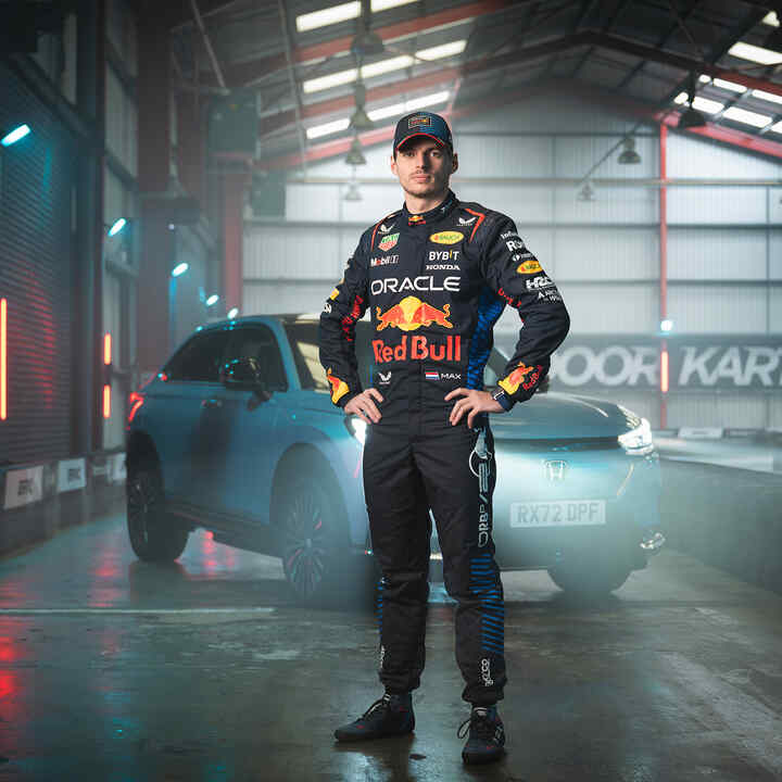 Max Verstappen standing next to a blue eny1 car parked behind him.